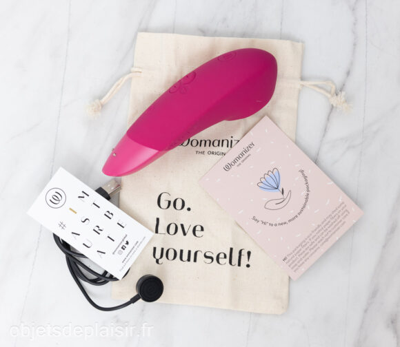 The Womanizer Enhance, its pouch, charging cable, and instruction manual